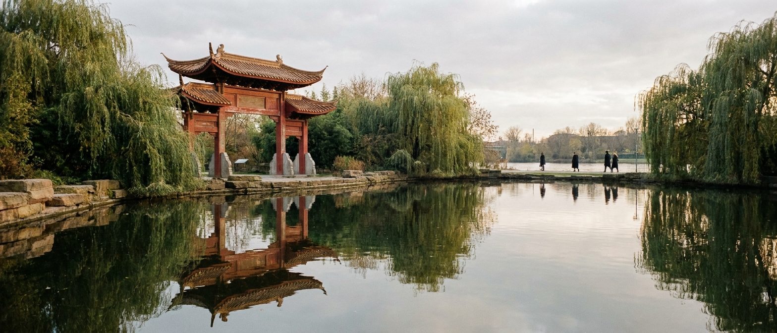 Chinesisches Gartentor aus rotem Holz mit geschwungenem Dach, gespiegelt in einem stillen Teich