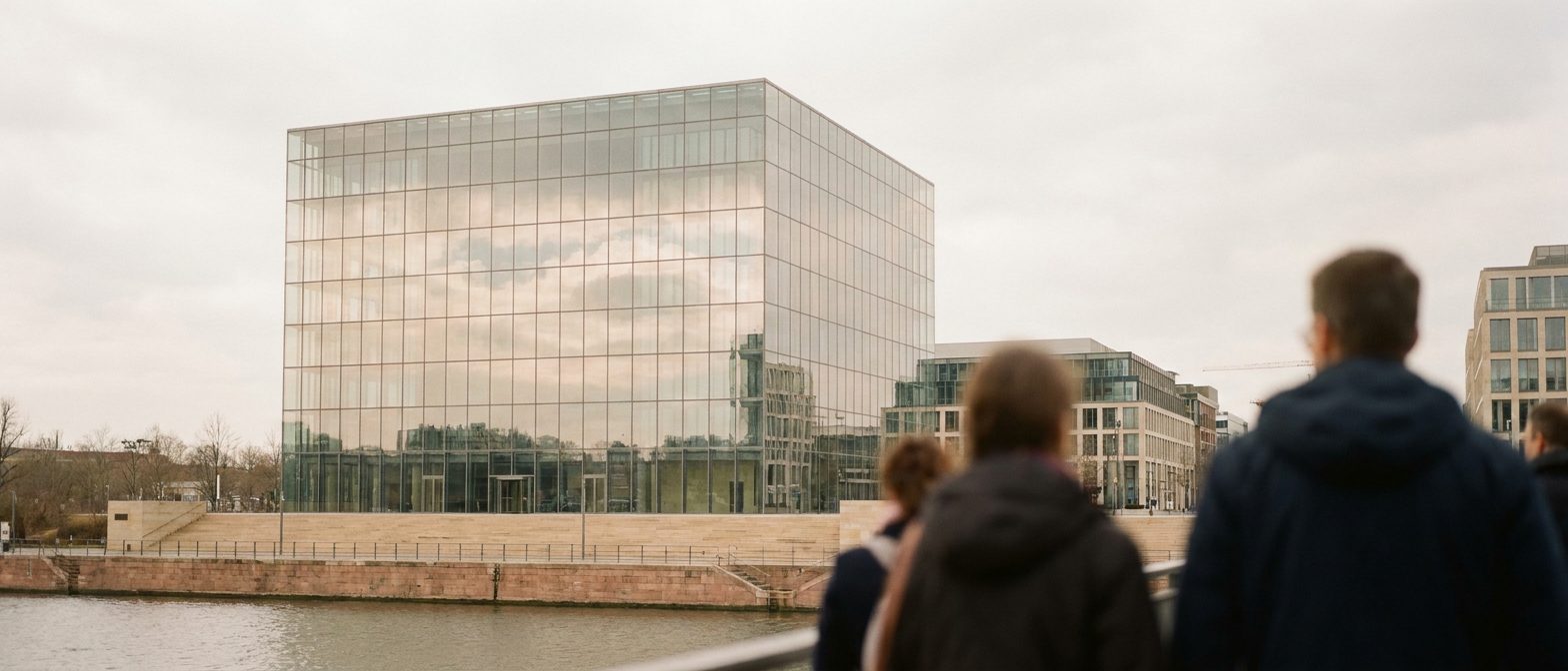 Der gläserne Würfelbau „The Cube" der Deutschen Börse in Eschborn spiegelt Wolken im Mittagslicht.