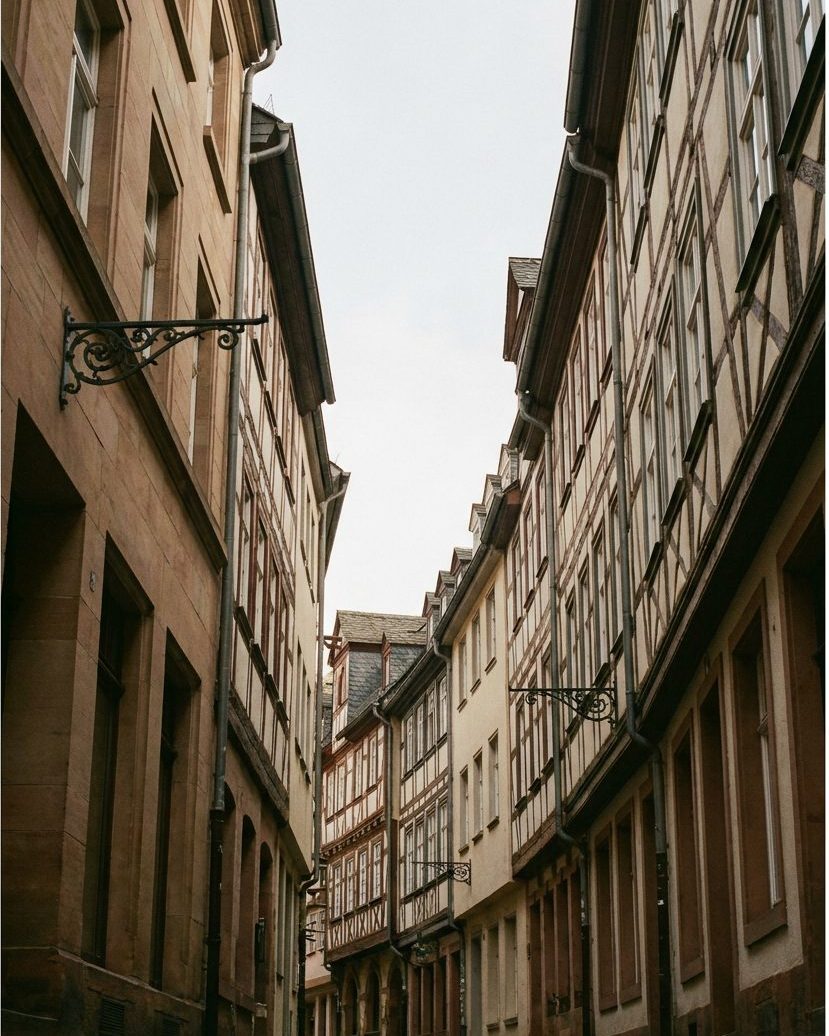Enge Gasse mit rekonstruierten Fachwerk- und Steinhäusern, Kopfsteinpflaster, Blick nach oben zum Himmel, Hochformat.
